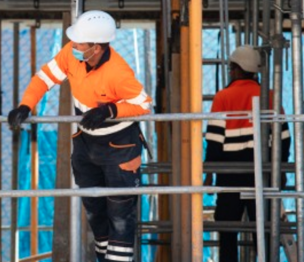 Two Constructions Workers in Surgical Maskers working amongst scaffolding