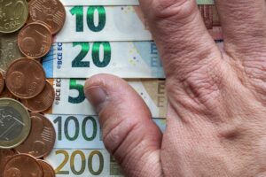 Hand fingers on background of neatly arranged stack of euro banknotes, currency bills worth ten